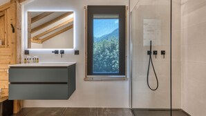 Un baño moderno con tragaluz, un espejo grande y una zona de ducha.