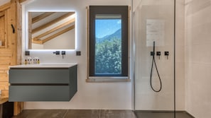 Un baño moderno con tragaluz, un espejo grande y una zona de ducha.