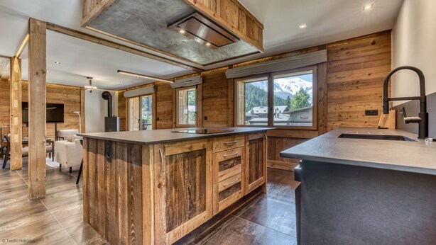 A modern kitchen with wooden cabinetry, a large island, and a view of mountains through the windows.