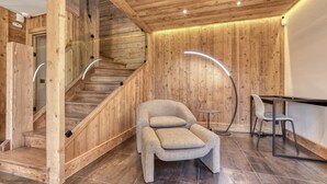 A wooden interior with a staircase, a cushioned chair, and a small table.