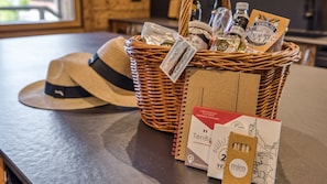 Un panier en osier rempli de divers objets, notamment un chapeau, des cartes postales et des bouteilles.