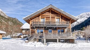 Una cabaña de madera con balcón, rodeada de montañas nevadas.