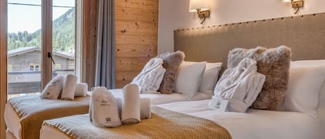 A hotel room with two beds, wooden paneling, a view of a mountain, and a headboard with a tufted design.