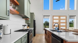 A modern kitchen with a central island, built-in appliances, and large windows offering a view of the outdoors. - Ranch & Relax - Sauna, Hot Tub + Stargazing Escape (Broken Bow)