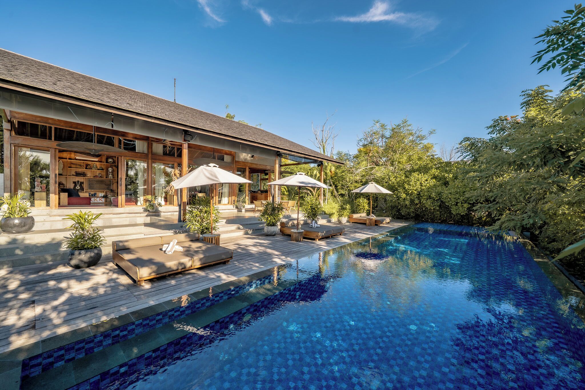 A modern house with a swimming pool, outdoor seating, and lush greenery.