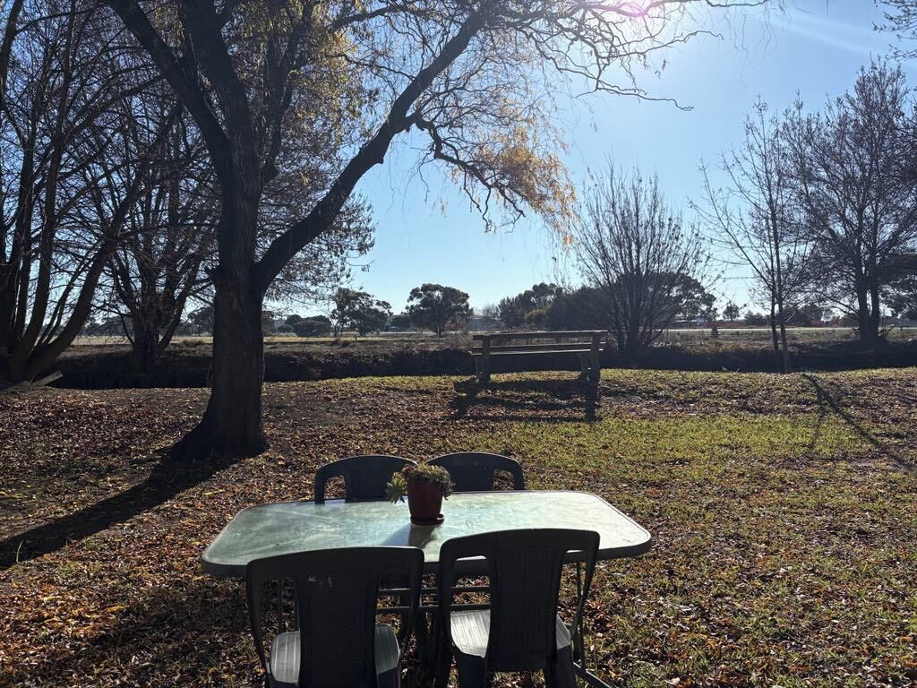 An outdoor table with chairs and a bench in a park.