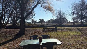Uma mesa ao ar livre com cadeiras e um banco em um parque.