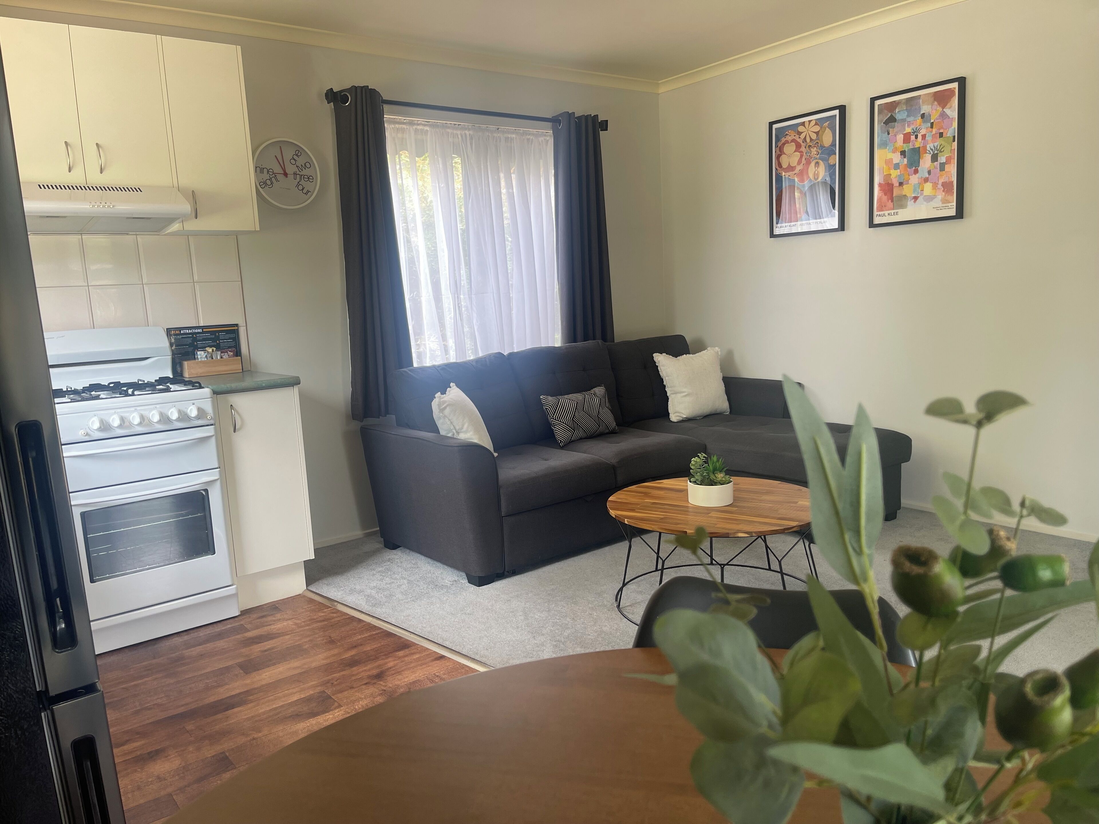 Un espacio habitable compacto con kitchenette, sofá, mesa de centro y comedor.