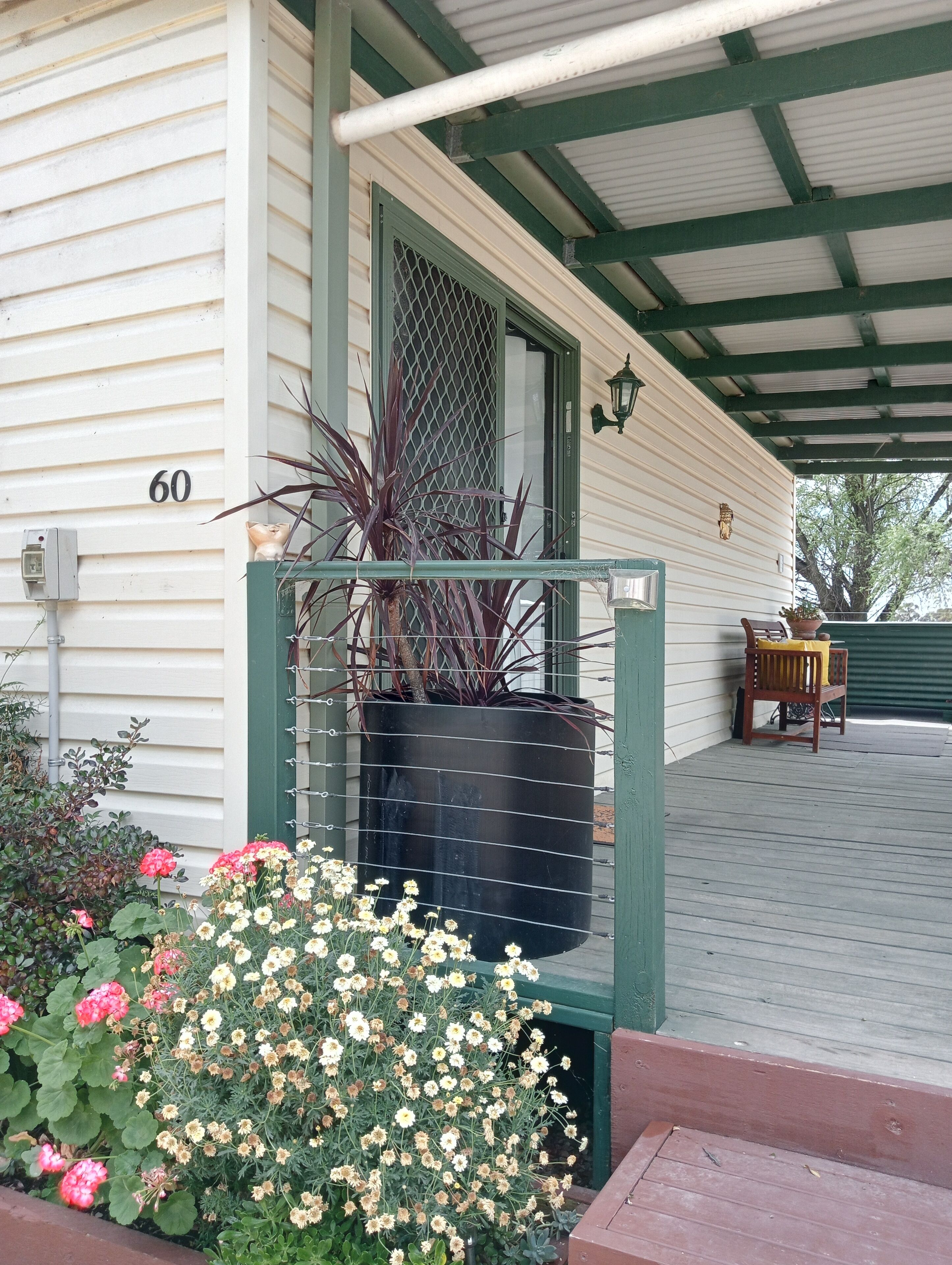 A covered porch with a wooden bench, a potted plant, and a number '60' on the house.