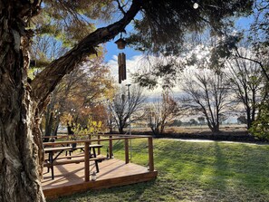 A wooden deck with picnic tables and benches, surrounded by trees and a grassy area. - Kerang Holiday Park (Kerang)