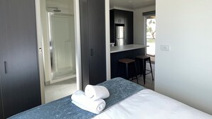 Un dormitorio moderno con cama, baño con ducha y kitchenette.