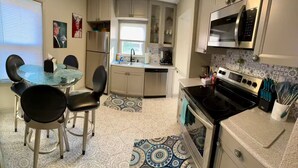 A compact kitchen with a dining area, featuring a refrigerator, microwave, stove, and a small sink. - Cozy Single-family house (Glendale)
