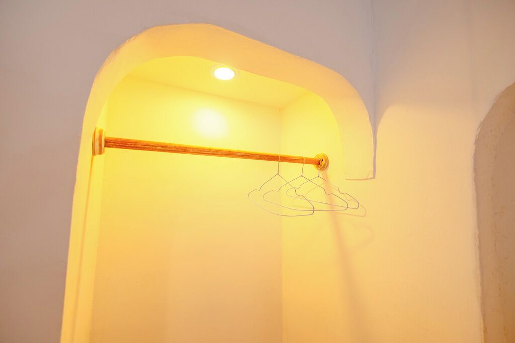 A room with a wooden towel rack and a hanging clothes rack.
