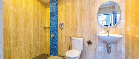 A modern bathroom with a checkered floor, a toilet, a sink with a mirror, and a shower area with a blue-tiled column.