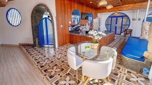 A modern interior with a wooden ceiling, a reception desk, a seating area, and a patterned floor. - Anny Guesthouse 2 by Ecommerceloka (Denpasar)