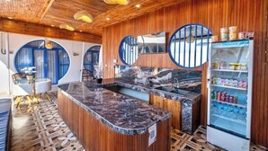 A modern kitchen with wooden accents, a marble countertop, and a refrigerator stocked with beverages. - Anny Guesthouse 2 by Ecommerceloka (Denpasar)