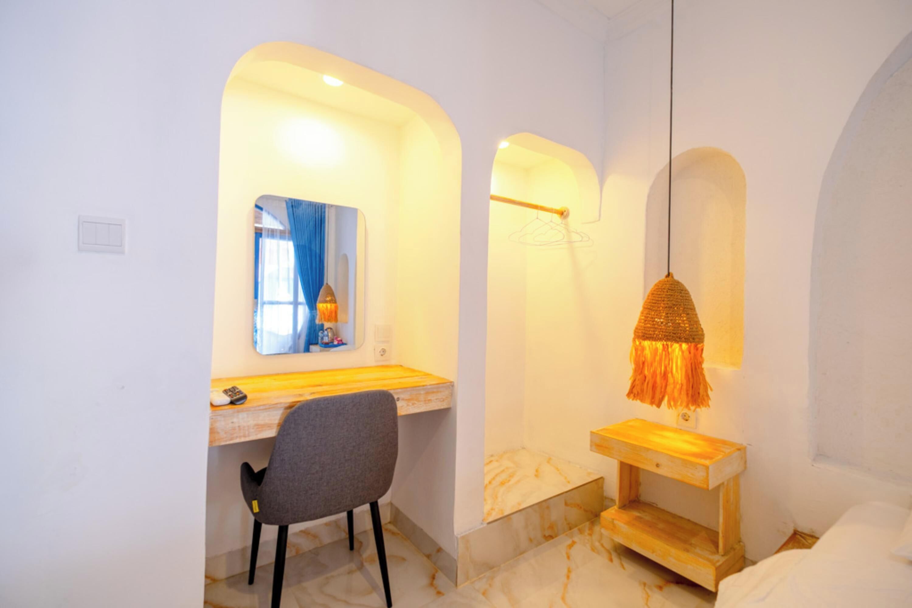 Un baño con piso de mármol, tocador de madera, espejo, toallero y lámpara colgante.