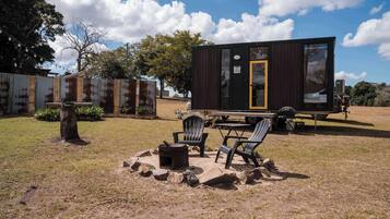 A small cabin with a deck, outdoor seating, and a fire pit.