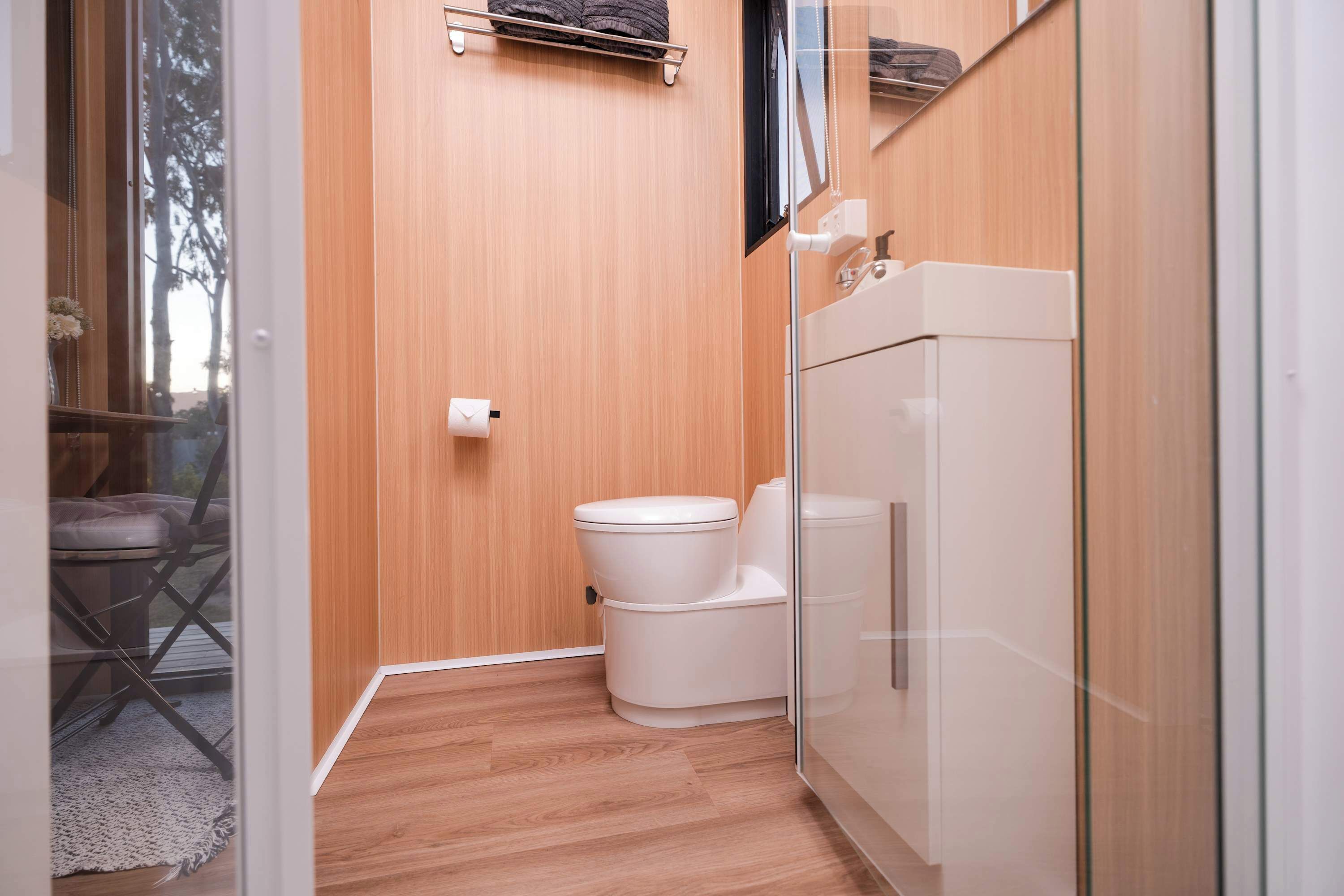 Un bagno compatto con il water, un porta asciugamani e una cabina doccia in vetro.