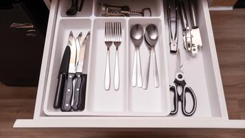 Un tiroir contenant divers ustensiles de cuisine, notamment des couteaux, des fourchettes, des cuillères et des ciseaux.