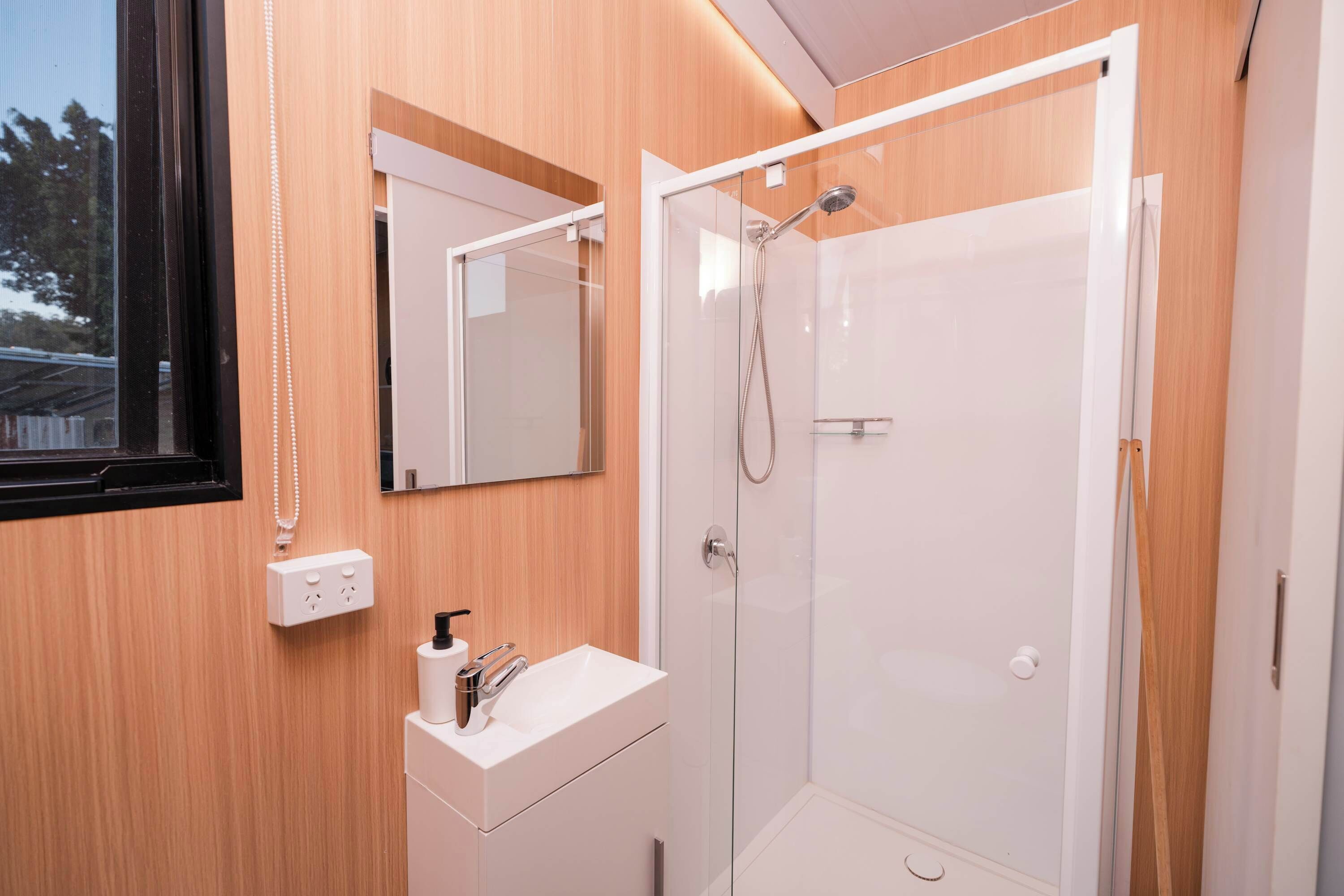 A modern bathroom with a glass shower enclosure, a white sink, and a mirror above the vanity.