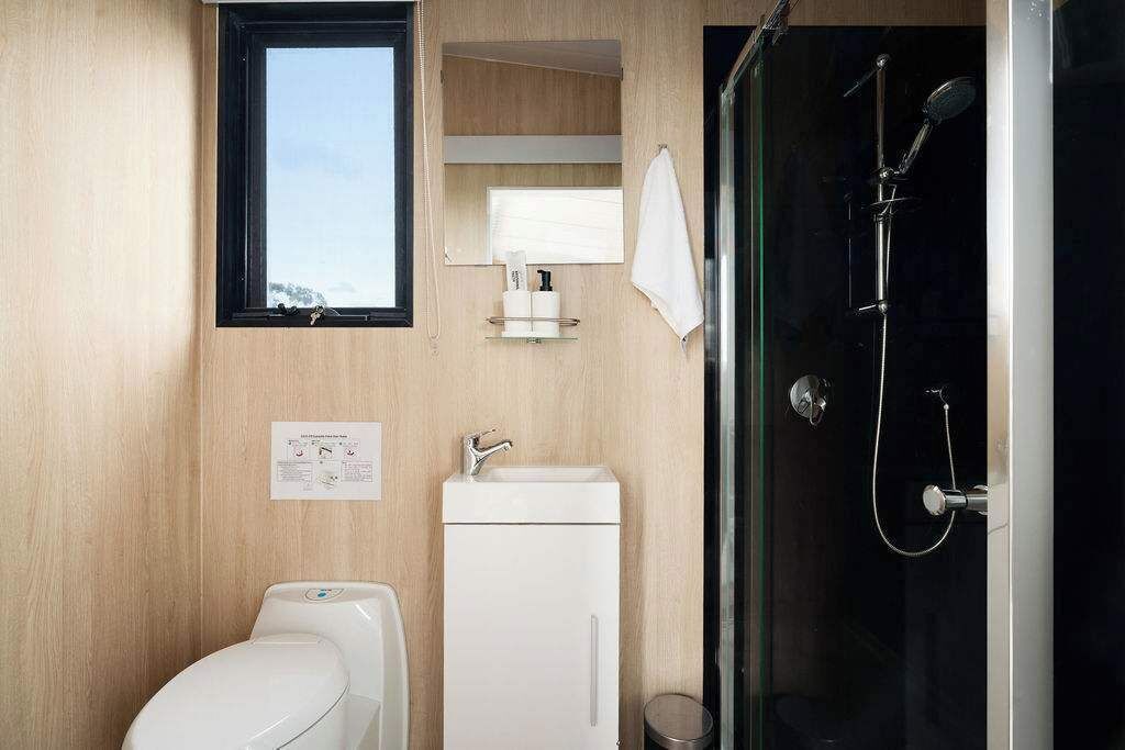A compact bathroom with a toilet, sink, and glass-enclosed shower.