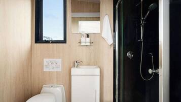 A compact bathroom with a toilet, sink, and glass-enclosed shower.