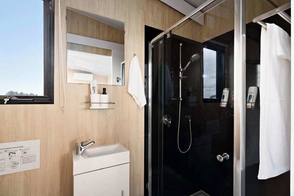 Une salle de bain moderne avec une douche à parois de verre, un lavabo blanc et un miroir au-dessus.