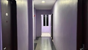 A long, narrow hallway with purple walls and a grey floor, leading to a door at the end. - Collection O KLIA Formerly Bary Inn. (Sepang)