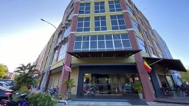 A multi-story building with a central entrance, large windows, and a flag. - Collection O KLIA Formerly Bary Inn. (Sepang)