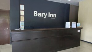A reception desk at Bary Inn with a dark wood finish, a black wall with the hotel's name, and several framed certificates or awards on the wall. - Collection O KLIA Formerly Bary Inn. (Sepang)