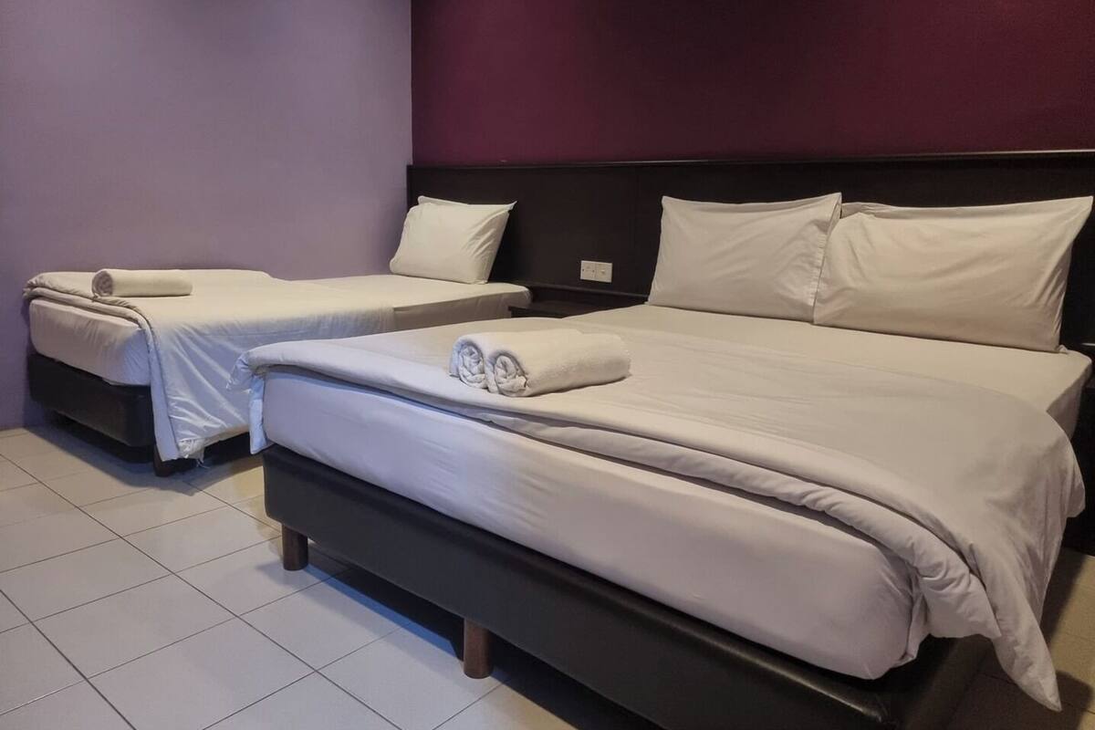 Una habitación de hotel con dos camas individuales y una cama más grande.