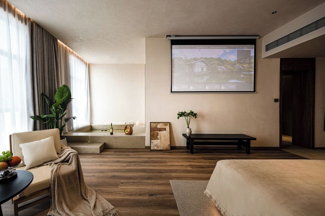 Un salon moderne comprenant un canapé, une table basse, un banc, un écran de projection et une grande fenêtre avec des rideaux.