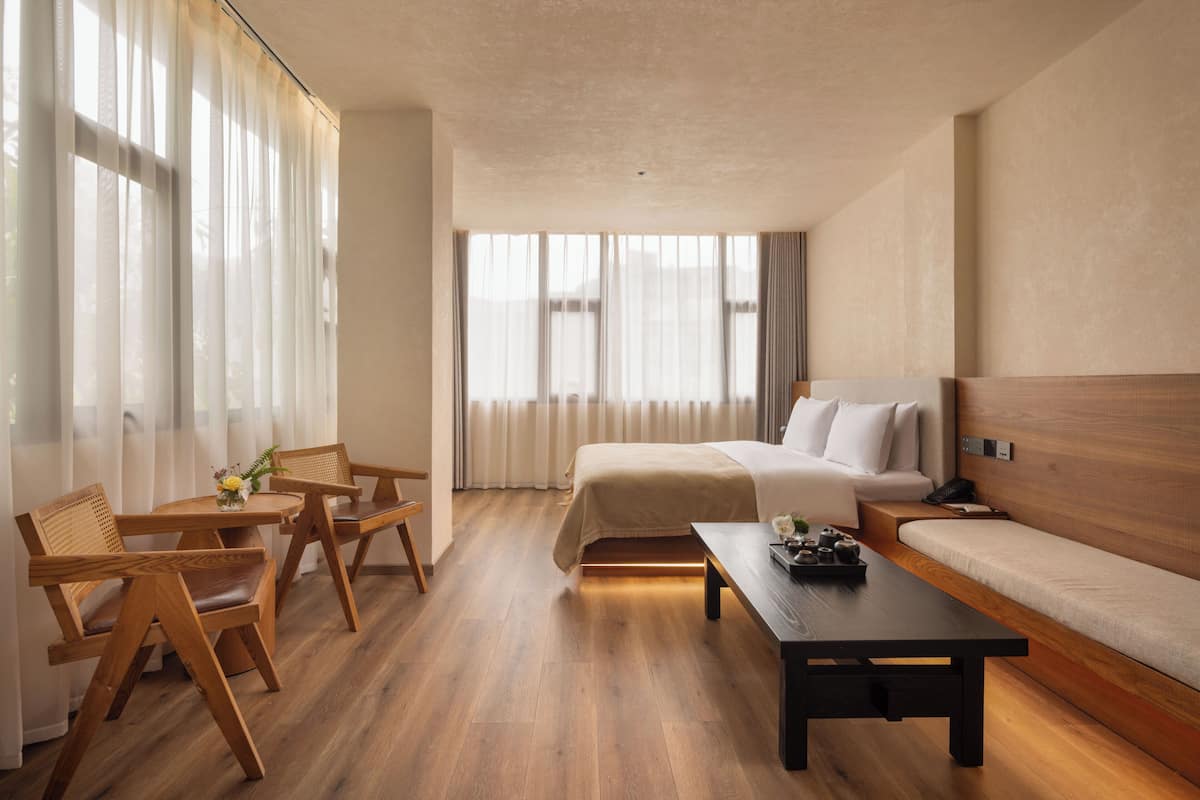 A hotel room with a bed, a sofa, a dining table, and two chairs.