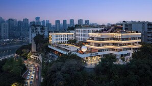 A multi-story hotel with a modern design, located in an urban area with a view of the city skyline. - Wanda Moments Chongqing Liziba (Chongqing)