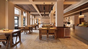 A spacious restaurant with wooden tables and chairs, a high ceiling with exposed beams, and large windows allowing natural light. - Wanda Moments Chongqing Liziba (Chongqing)