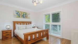 Een slaapkamer met een houten bed, nachtkastjes, een lamp en een raam met zonwering.