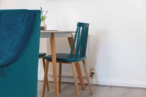 A teal chair and table in a room with a white wall and wooden flooring. - Albyn Retreat - Donnini Apartments (Prestwick)
