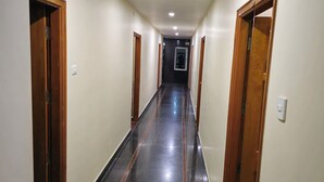 A corridor with wooden doors and a tiled floor. - HOTEL KSR GRAND (Srikalahasti)