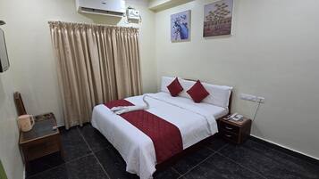 Habitación de hotel ordenada con cama, mesita de noche, teléfono y aire acondicionado instalado en la pared.