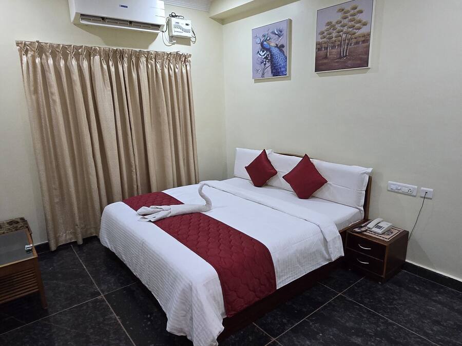 Habitación de hotel ordenada con cama, mesita de noche, teléfono y aire acondicionado instalado en la pared.