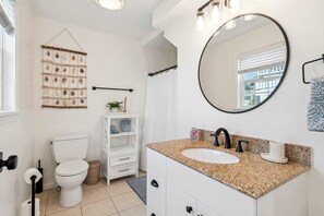 Ein modernes Badezimmer mit Toilette, Waschbecken mit Granitplatte, großem Spiegel und einer Wanddekoration.
