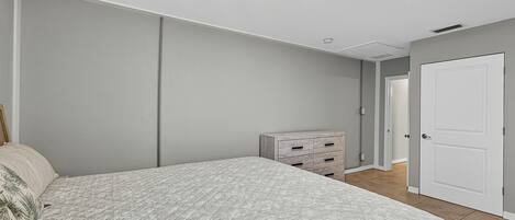 Un dormitorio con cama, cómoda y puerta.