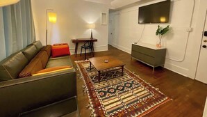 A modern living room with a sofa, a coffee table, a TV, and a dining area.