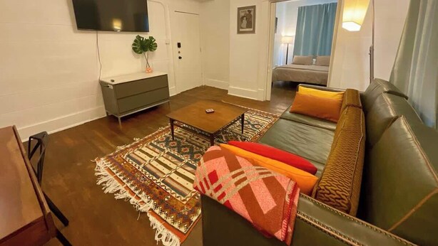 A living room with a sofa, coffee table, and TV mounted on the wall.