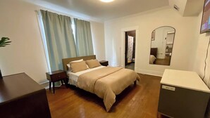 A bedroom with a bed, bedside table, dresser, and a mirror.