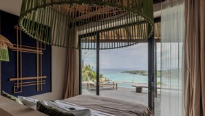 Un dormitorio con una cama grande, vista al océano y un balcón con terraza de madera.