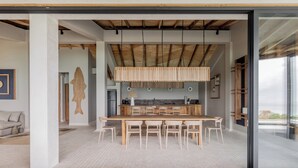 Una cocina moderna con una isla grande, sillas de madera y un lámpara colgante.