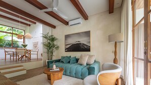 A modern living room with a teal sofa, wooden coffee table, and a large window with curtains. - Villa BUMI - Designer Villa 10 min to the Beach (Bali)