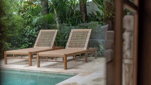 Two wicker lounge chairs by a poolside, surrounded by lush greenery. - Villa BUMI - Designer Villa 10 min to the Beach (Bali)